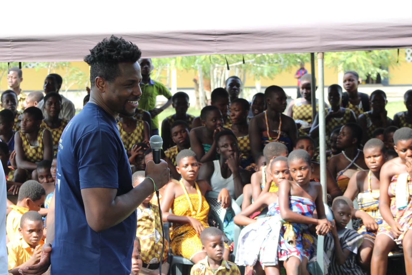 Godwill speaks with the community under a tent in Ghana