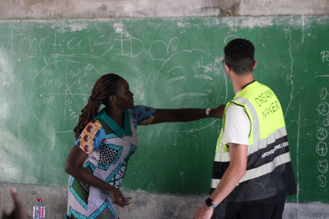 A volunteer helps students in Ghana name their emotions on the chalkboard
