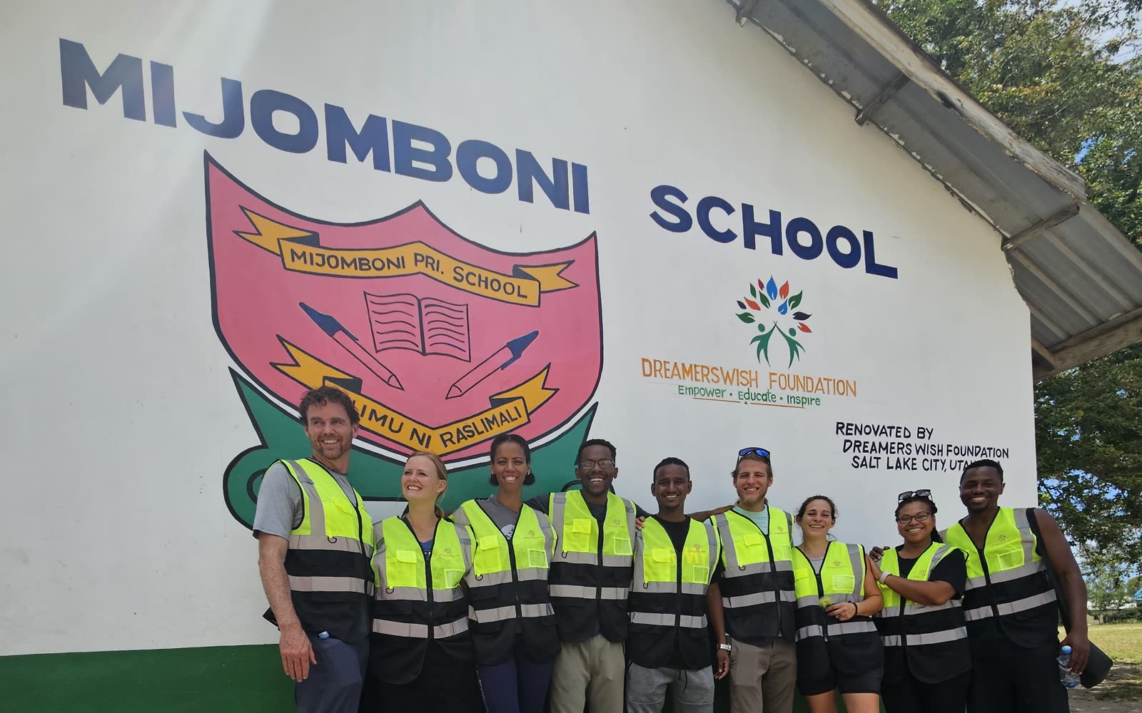 Before: the Mijomboni School wall with the school crest and the volunteer team