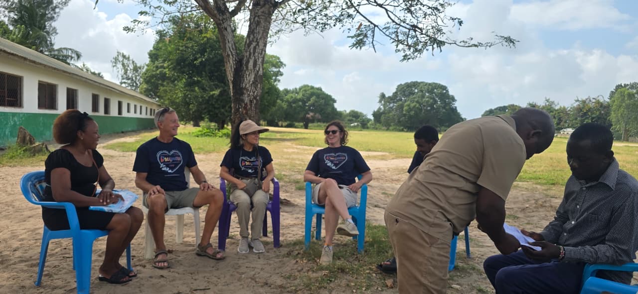Dreamers Wish volunteers meeting with local partners under a tree at the school