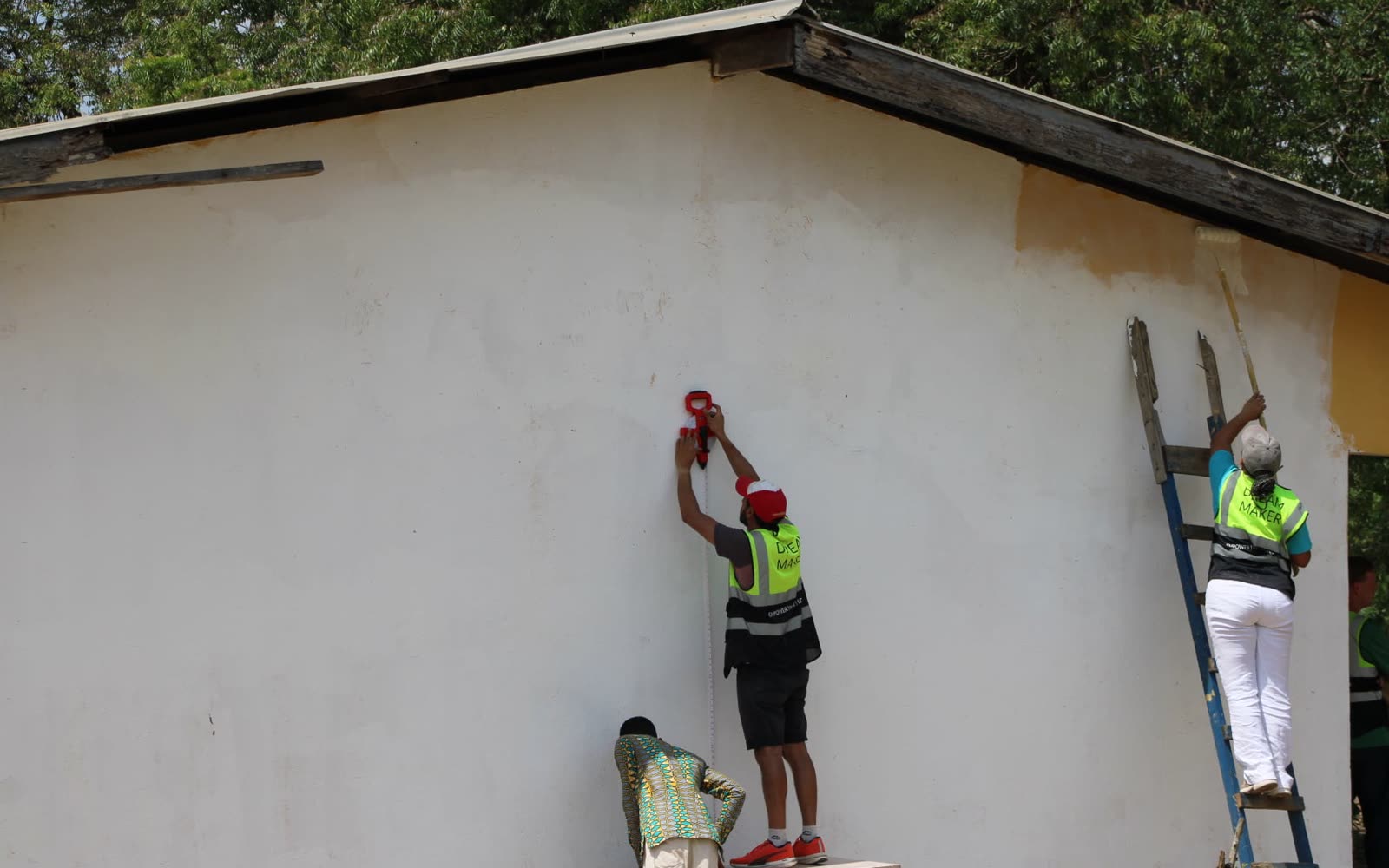 Before: volunteers on ladders priming a white school wall