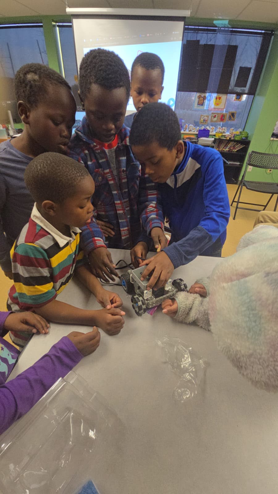 A student driving a VEX robot through a course of colored game pieces