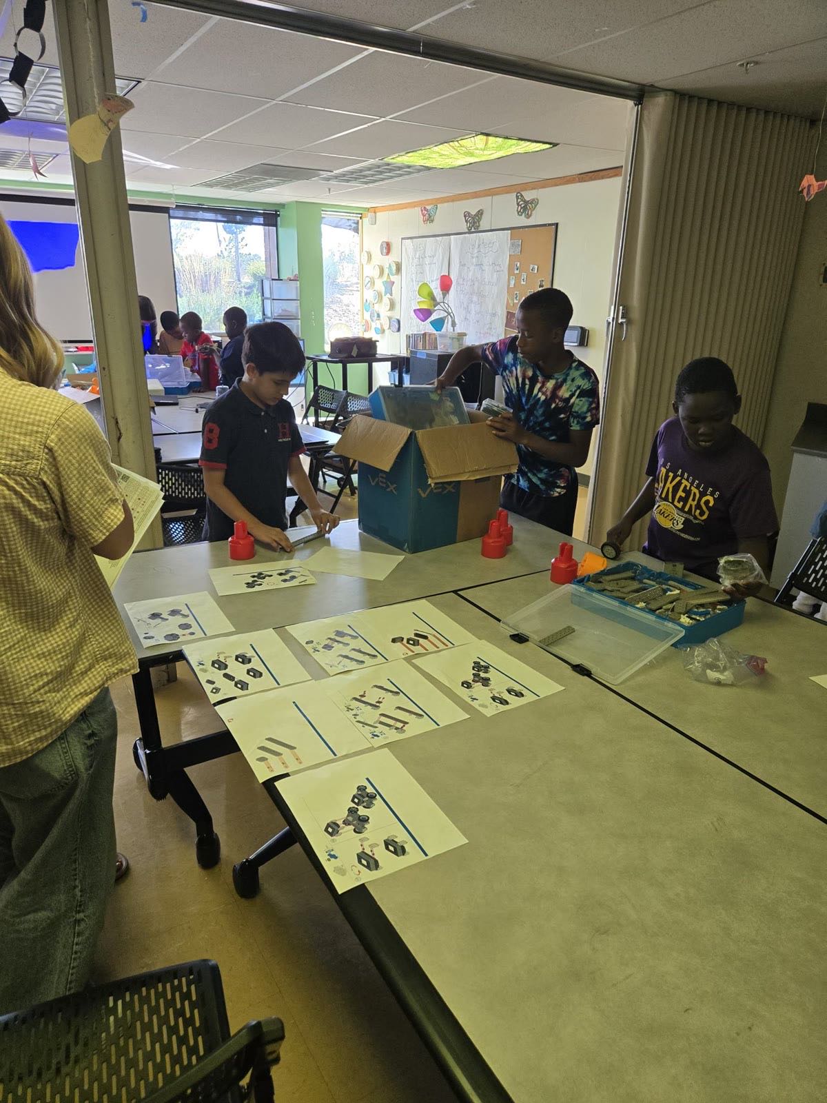 Students building VEX robots with step-by-step instruction sheets