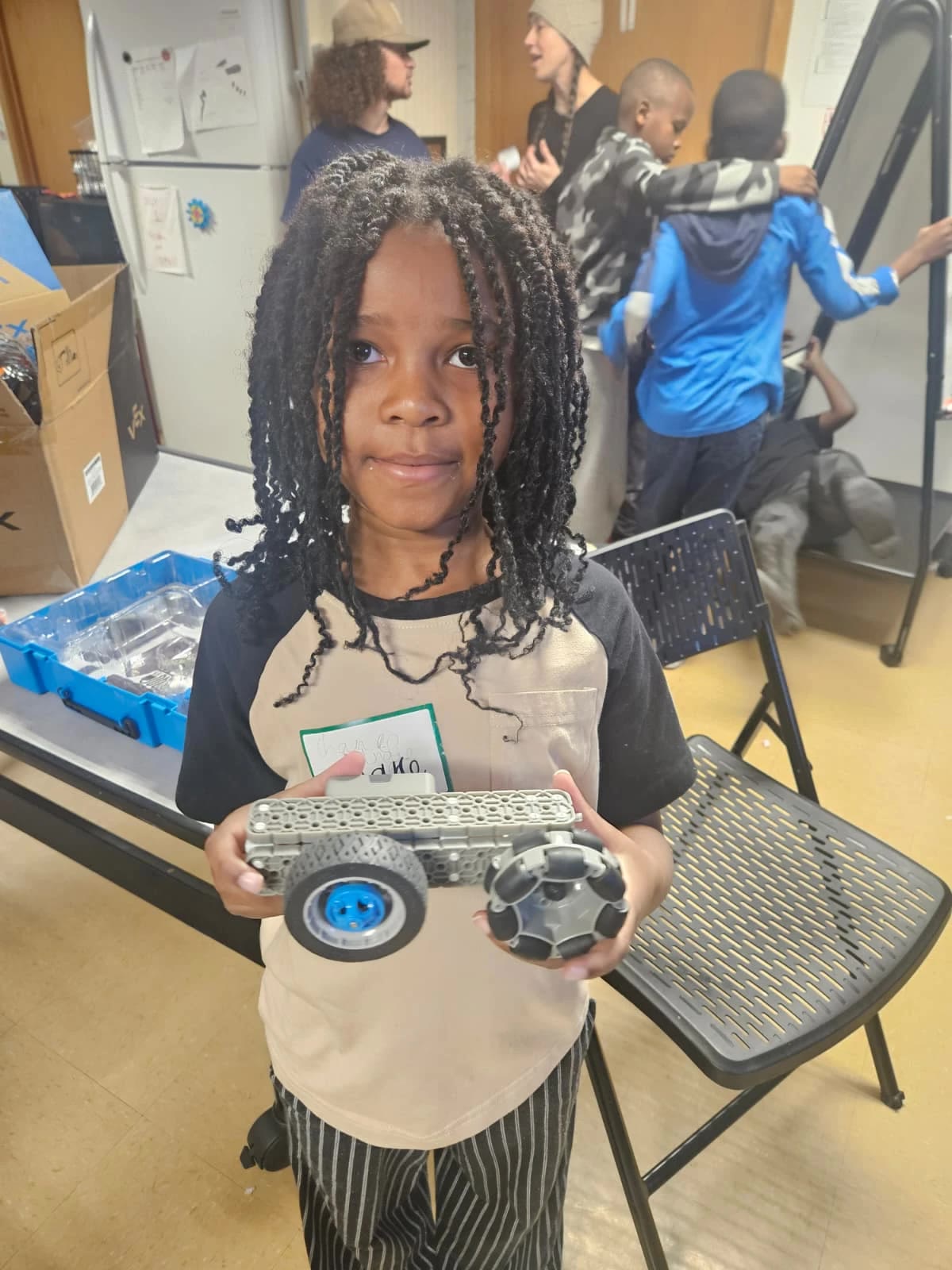 A young student proudly holding the VEX robot she built